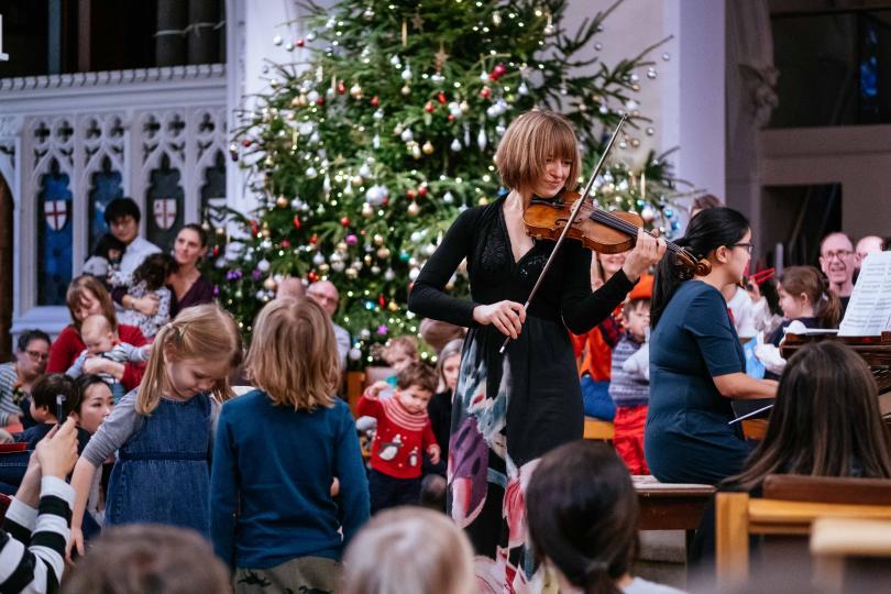 Violinist performing for children at a Christmas concert