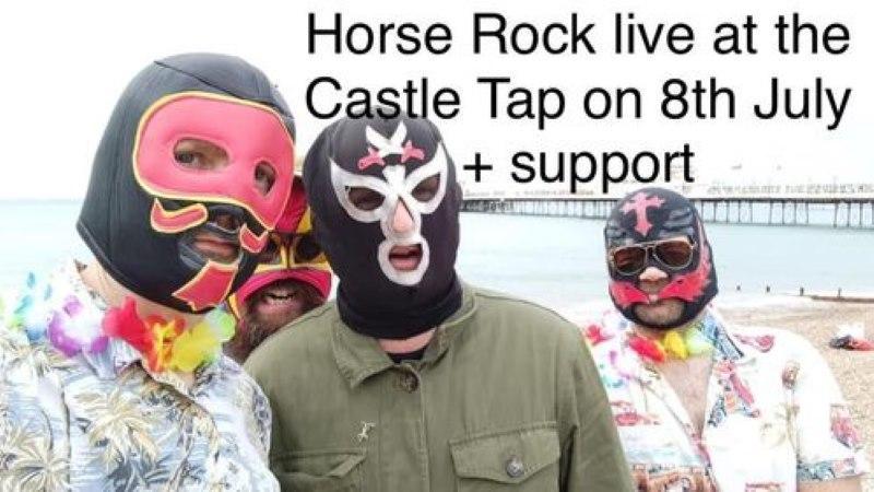 Three people in luchador masks are standing on the seaside looking at the camera