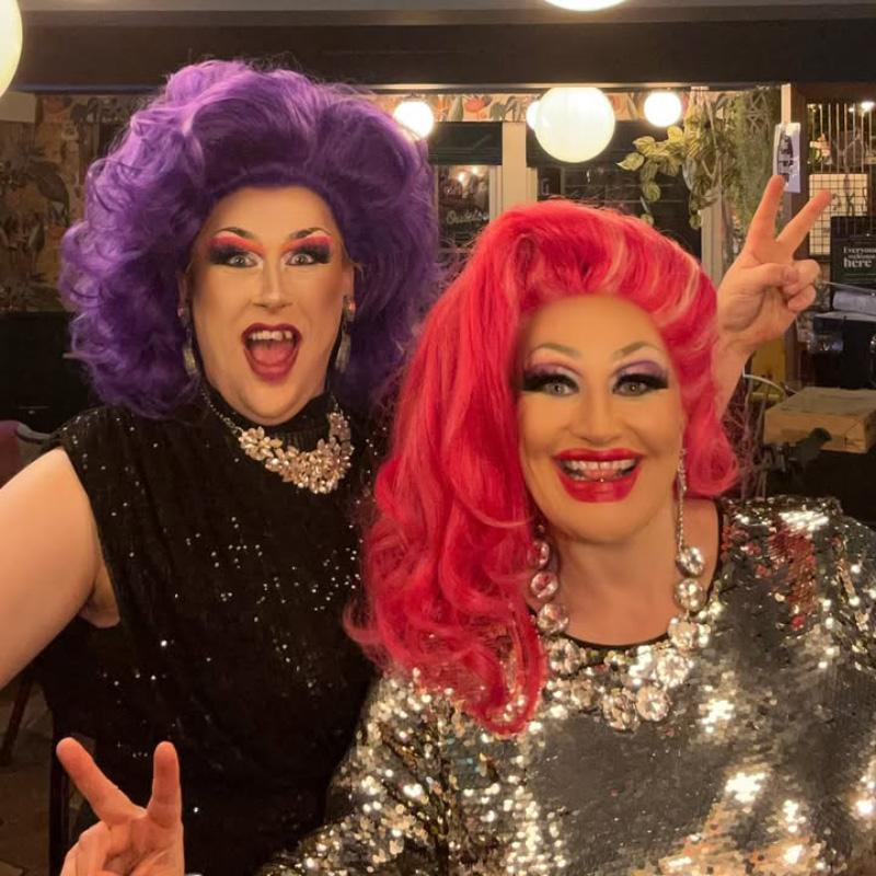 Drag queens Miss Charley O'llocks & Grace Anatomy in sparkly dresses, big wigs and big make up