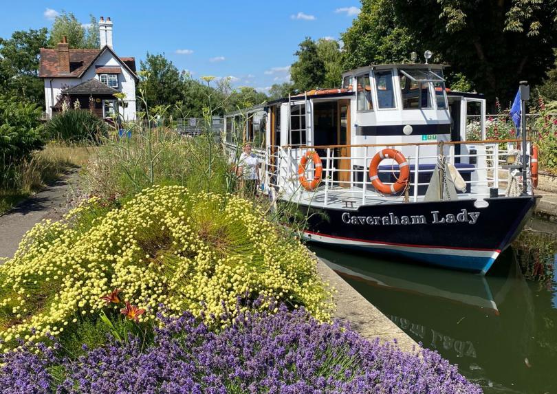 Pretty Goring lock with purple heather flowers, with Caversham Lady boat on a sunny day