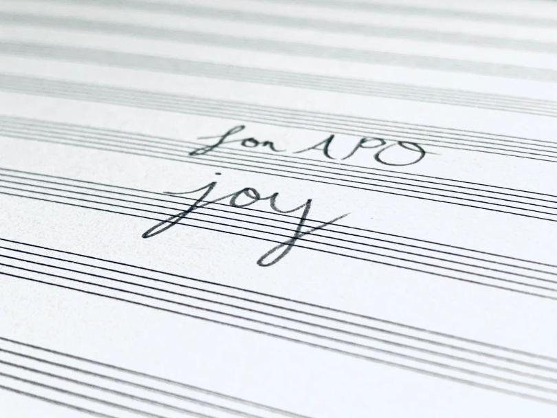 A handwritten text: For APO Joy on the music score