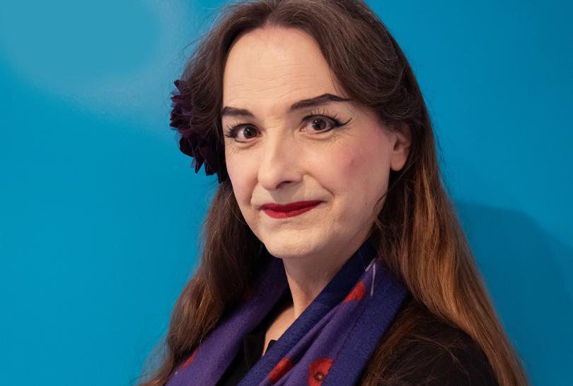 Photo of Alice d'Lumiere, a transwoman with pale make up and a flower in her hair