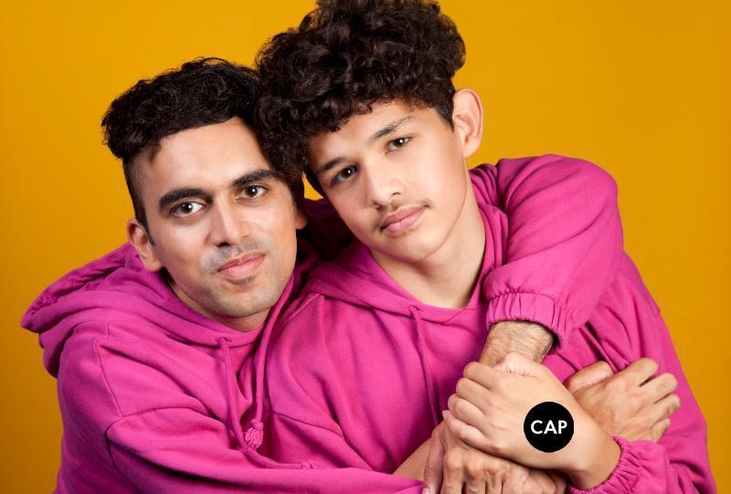 Photo of Vijay Patel and their brother wearing pink hoodies in front of an orange backdrop