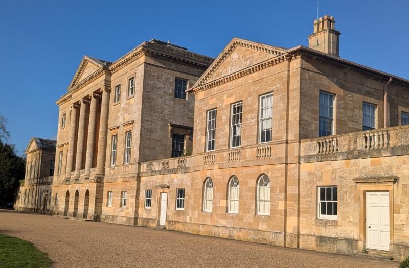 The front of Basildon Park manor house in the sunshine with a beautiful blue sky.