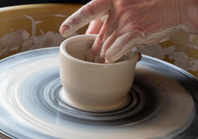Hand throwing a pot at the wheel