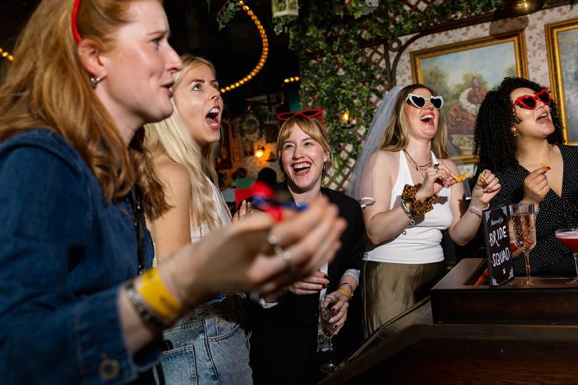 Women on a hen do paying darts