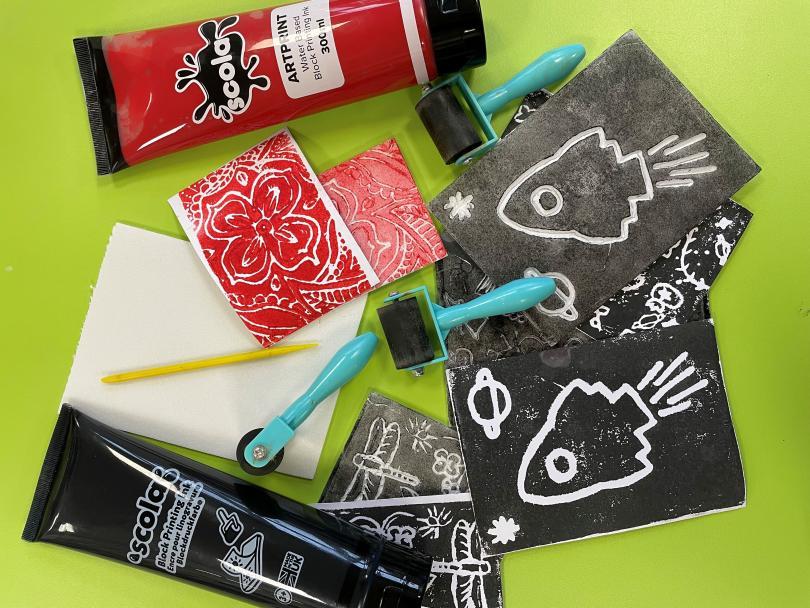 Image of assorted red and black paints, ink pads, sponges and examples of scratched art work. 