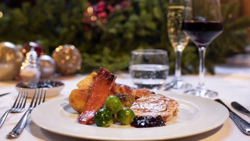 The image shows a roast dinner on a plate. There's a Christmas tree in the background.