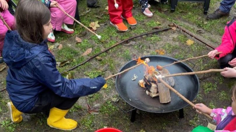 Families in the MERL garden toasting marshmallows on the campfire