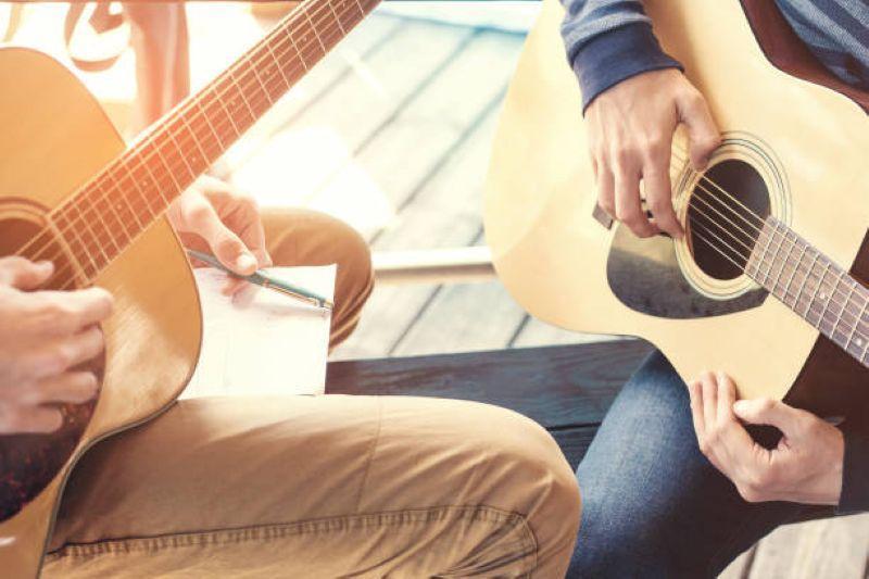student and teacher holding guitars
