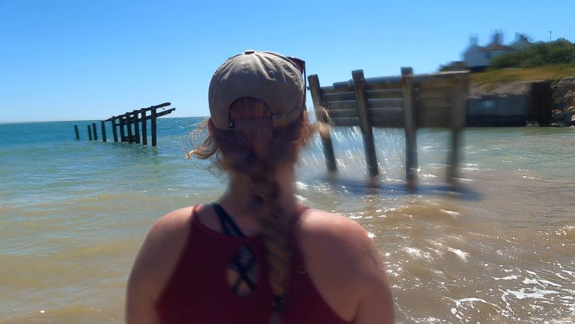 Woman standing by the sea with her back to the camera