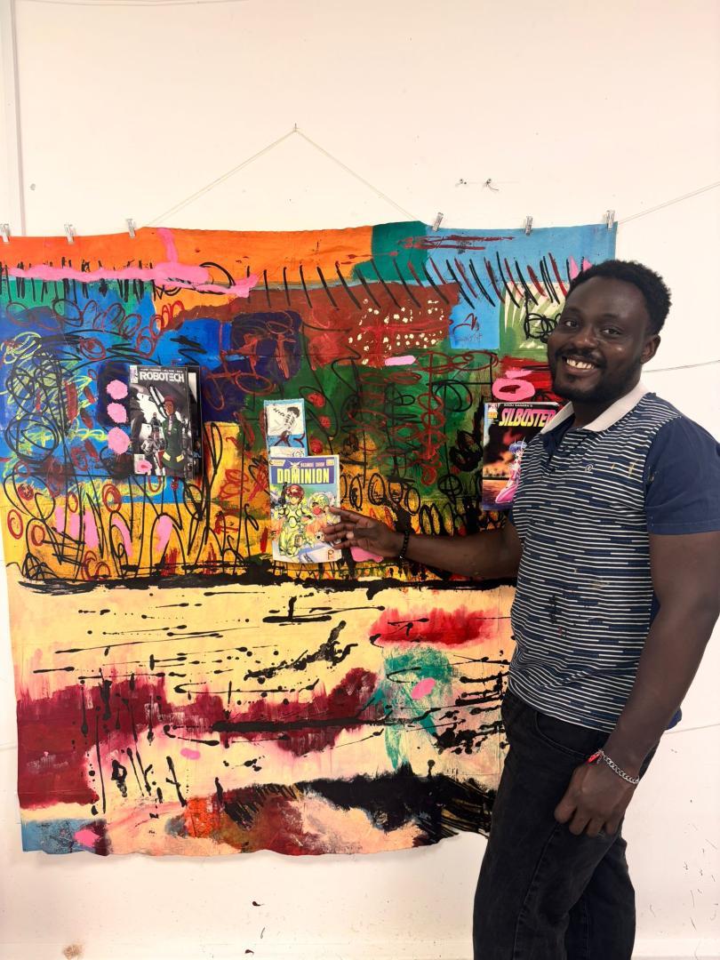 abstract painting on wall with young artist stood in front