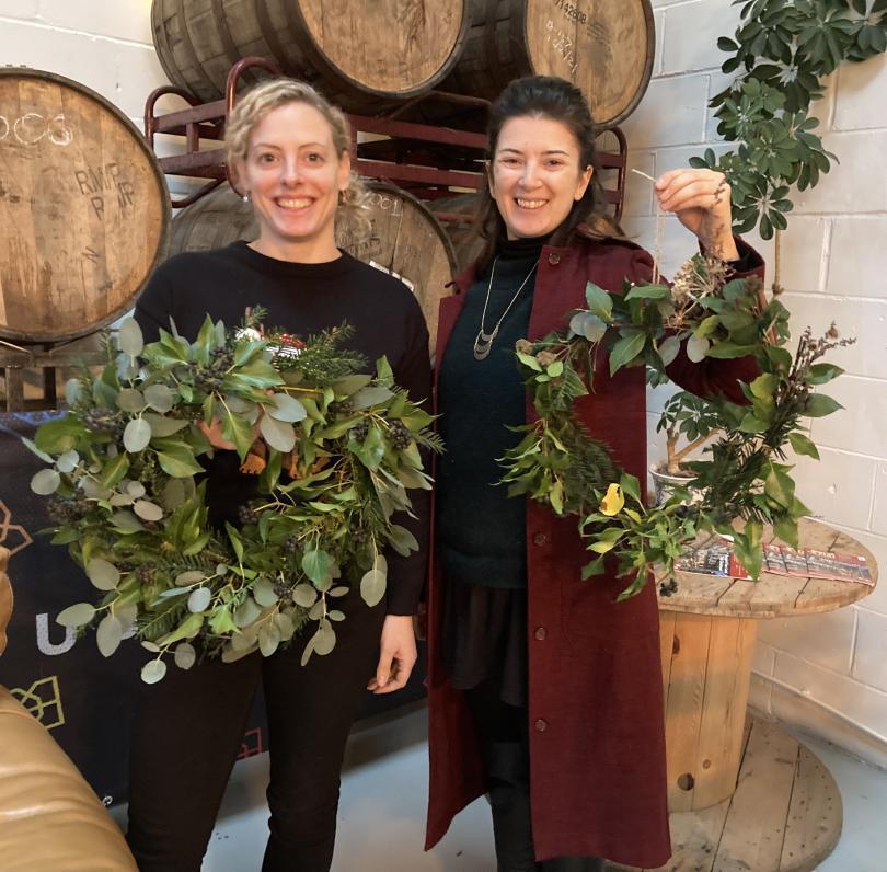 2 women proudly holding natural Christmas wreaths at Double Barrelled Taproom Tilehurst Reading