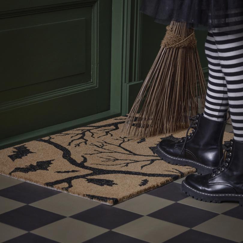 Halloween decorated door mat with trick or treater waiting at the door