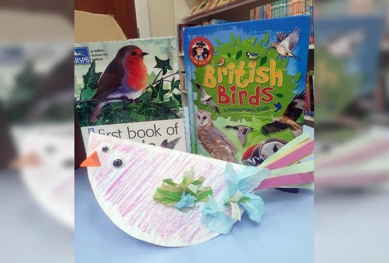 Photograph of a bird made from a paper plate in front of two bird books