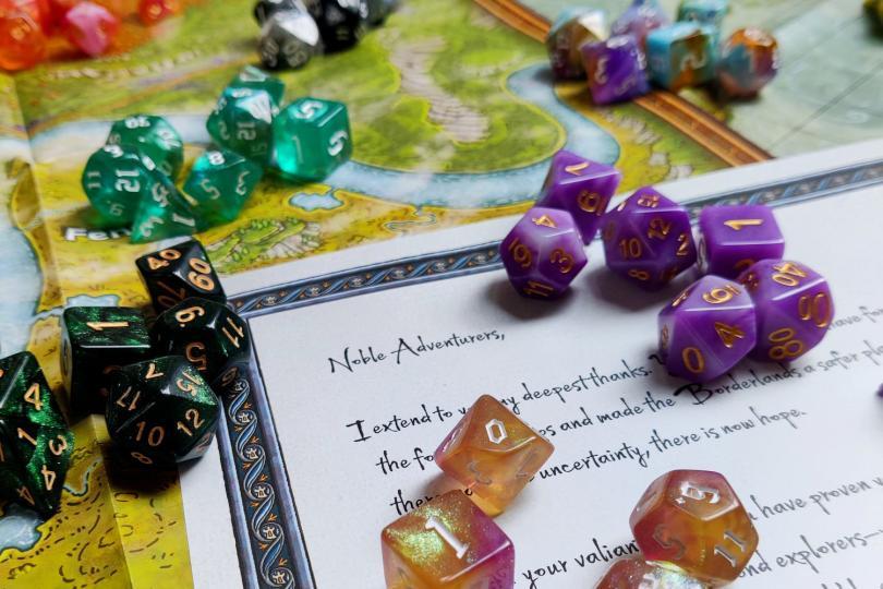 Colourful dice are laid out against a map and a letter