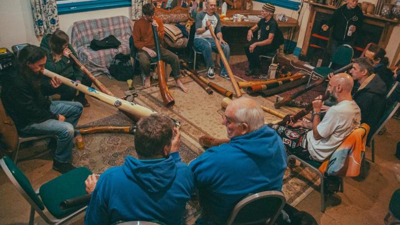 People sat in a circle playing didgeridoos