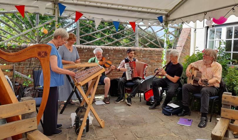 Photo of the Twagger Band playing at a folk club. They are singing and playing a variety of traditional instruments.
