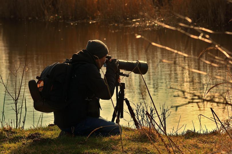 Wildlife photographer crouching by the riverside