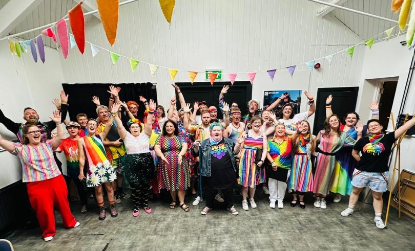 The chorus celebrates in rainbow outfits 