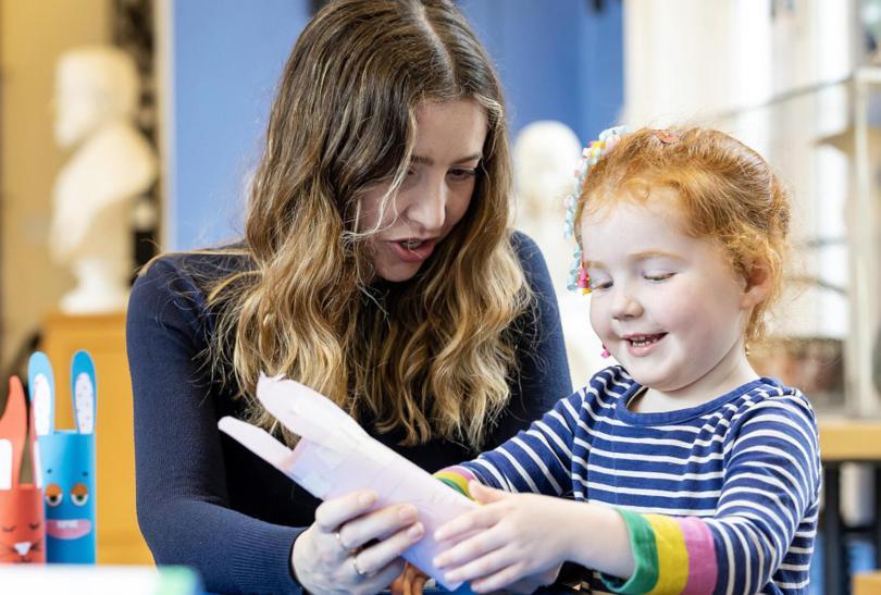 A child making crafts at Reading Museum, supported by a member of staff