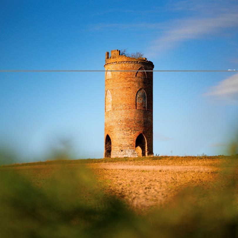 image of a tower in a field highlighted against a blue sky