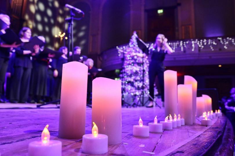 Candles on stage in Reading Concer Hall, with a choir out-of-focus in the background