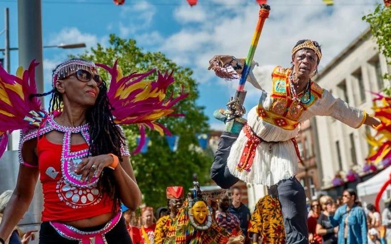 Performers in carnival outfits walking down Broad Street
