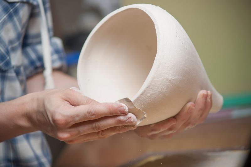 Hands shaping a clay pot