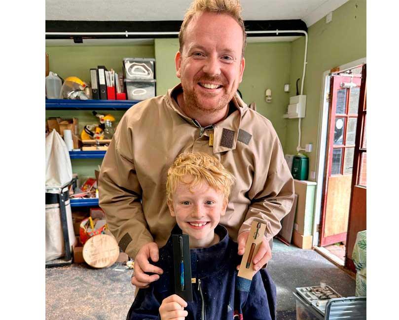 Father and son smiling and holding their handmade pens.