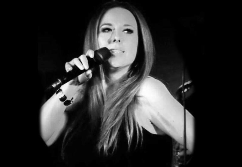 Black and white photo of singer Debby Bracknell. She has long hair and is singing into a microphone