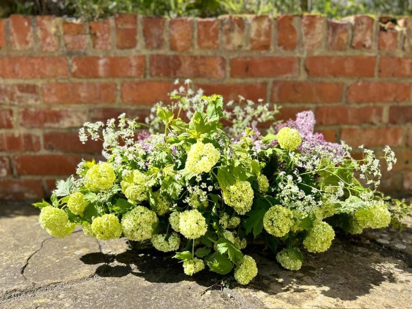 Wild vase arrangement of Spring flowers in green, lilac and white