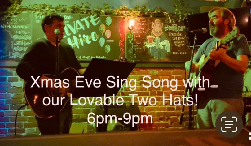 two men on stage playing acoustic guitars