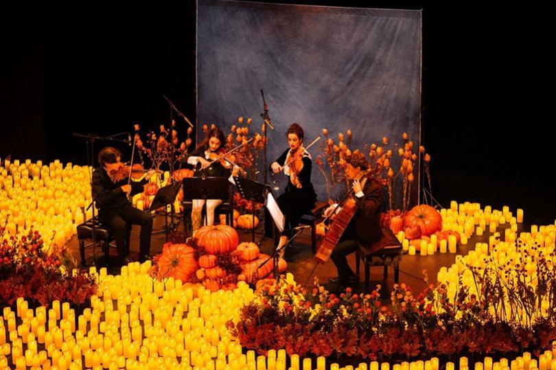 String quartet surrounded by candles and pumpkins