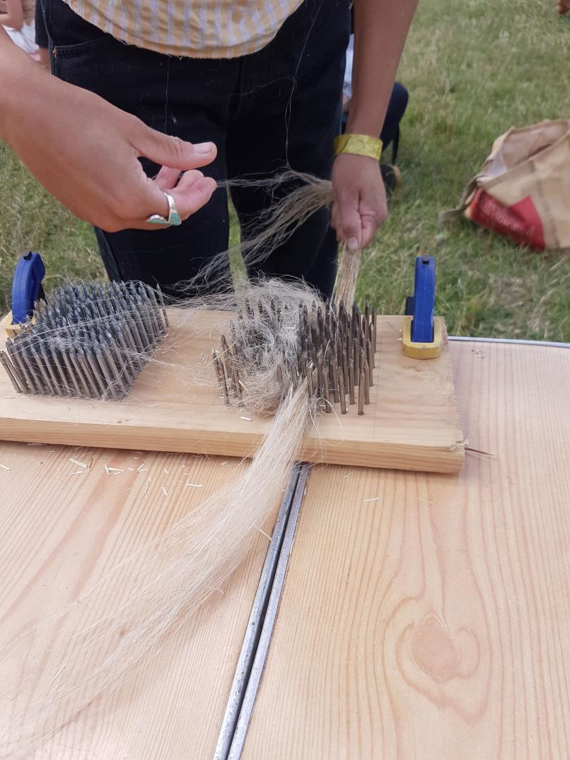 A person using a hackle with flax