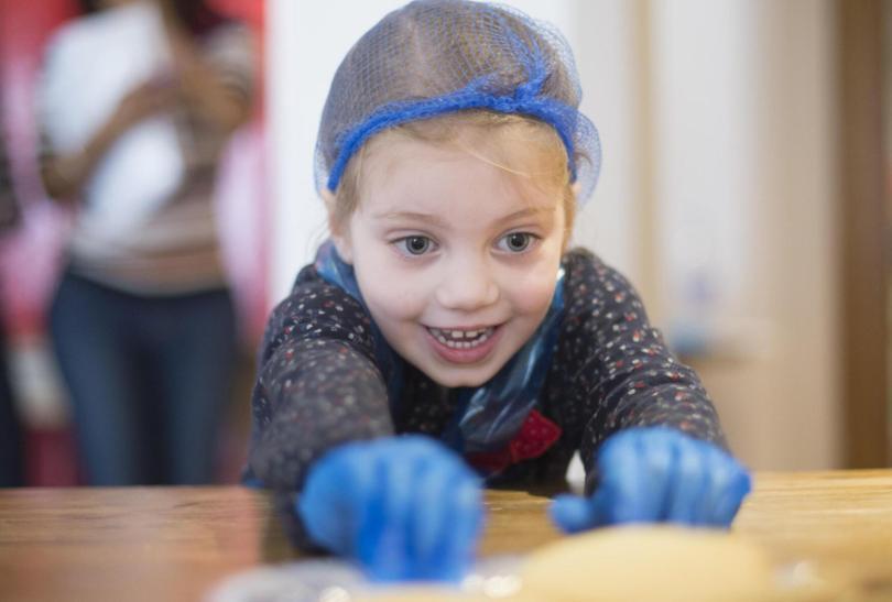 Young girl in a hairnet and plastic gloves, smiling