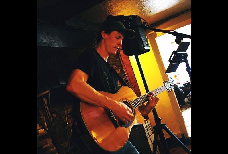 Singer Harry J playing an acoustic guitar in a pub