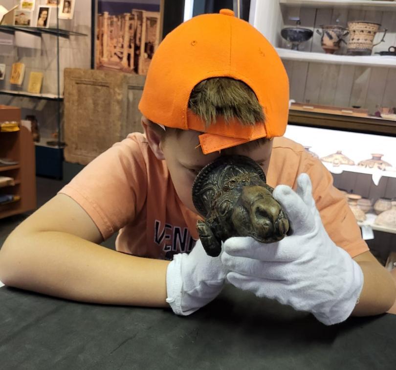 A child in an orange baseball cap examining a bronze statue
