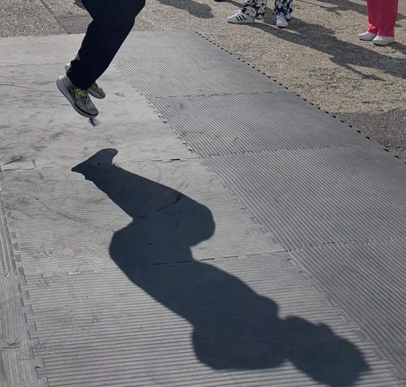  photo of a dancer jumping the air with only their feet and full shadow on the floor visible.