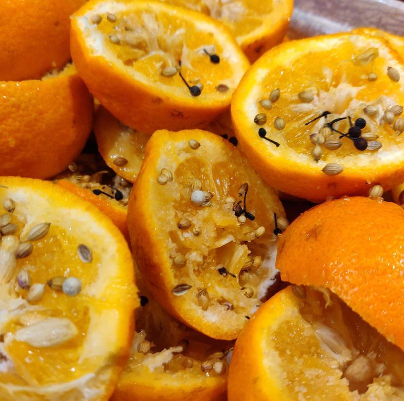 A pile of slices of oranges covered in a smattering of spices and sugar