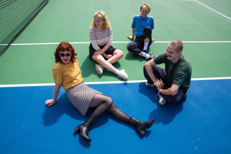Band pic of Pip blom sitting on a tennis court