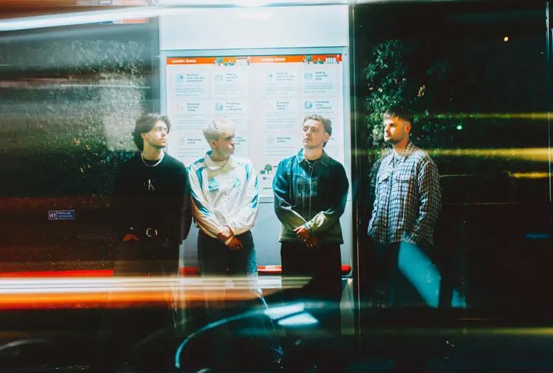 Only the Poets band members standing in a bus stop