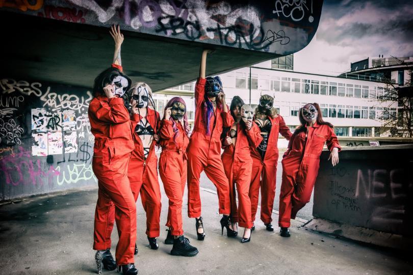 Women in Slipknot-style orange jumpsuits and horror masks, some with sexy burlesque outfits peeking out