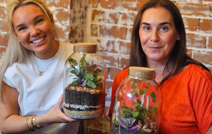 Two women smiling and holding terrariums