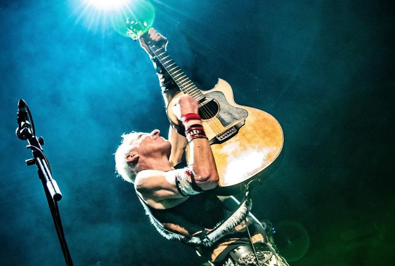 TV Smith holding a guitar on stage