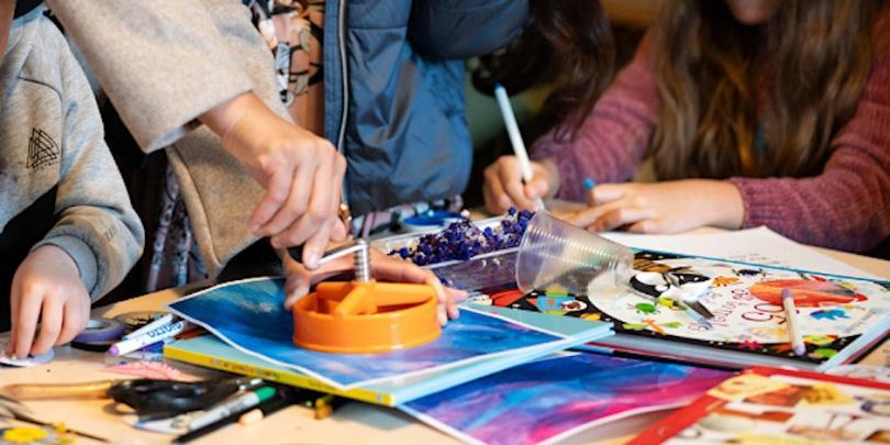 people creating art in a workshop, seen in close up with their hands on the table