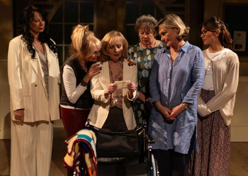 Cast of Calendar Girls reading note on stage.