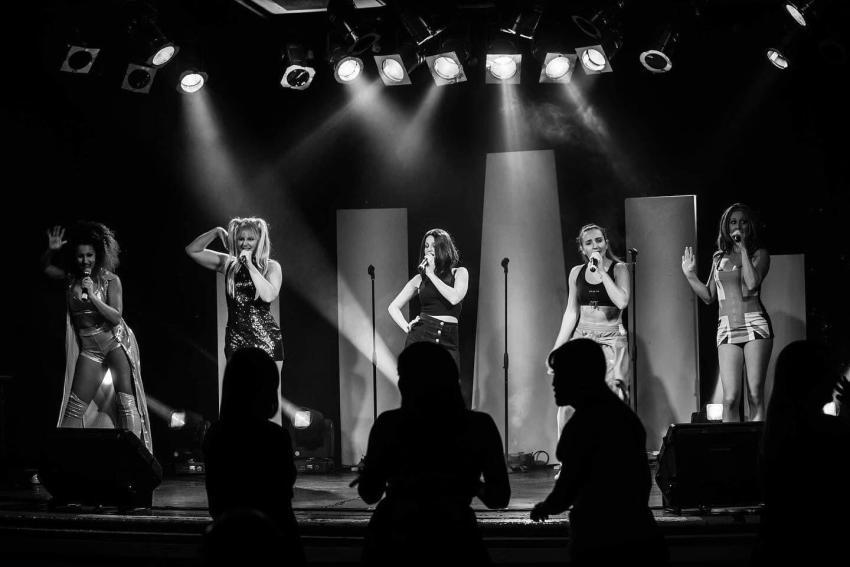 The image shows The Spicey Girls on stage performing.