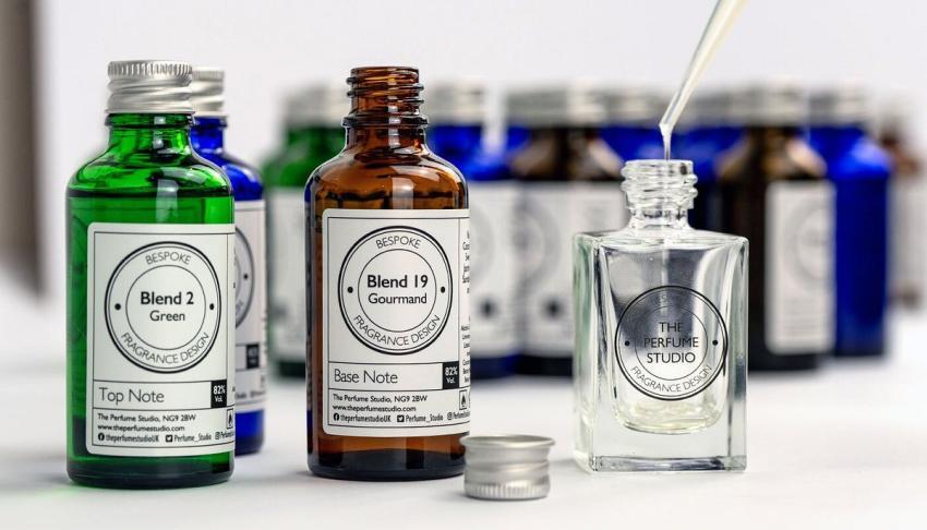 Glass bottles containing perfume next to an empty transparent perfume atomiser