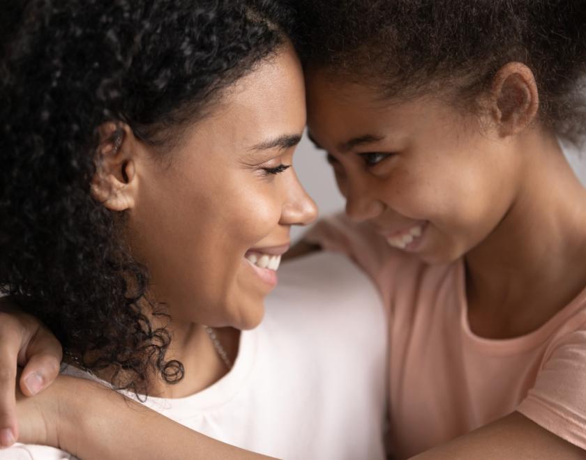 A mother and daughter smiling and cuddling